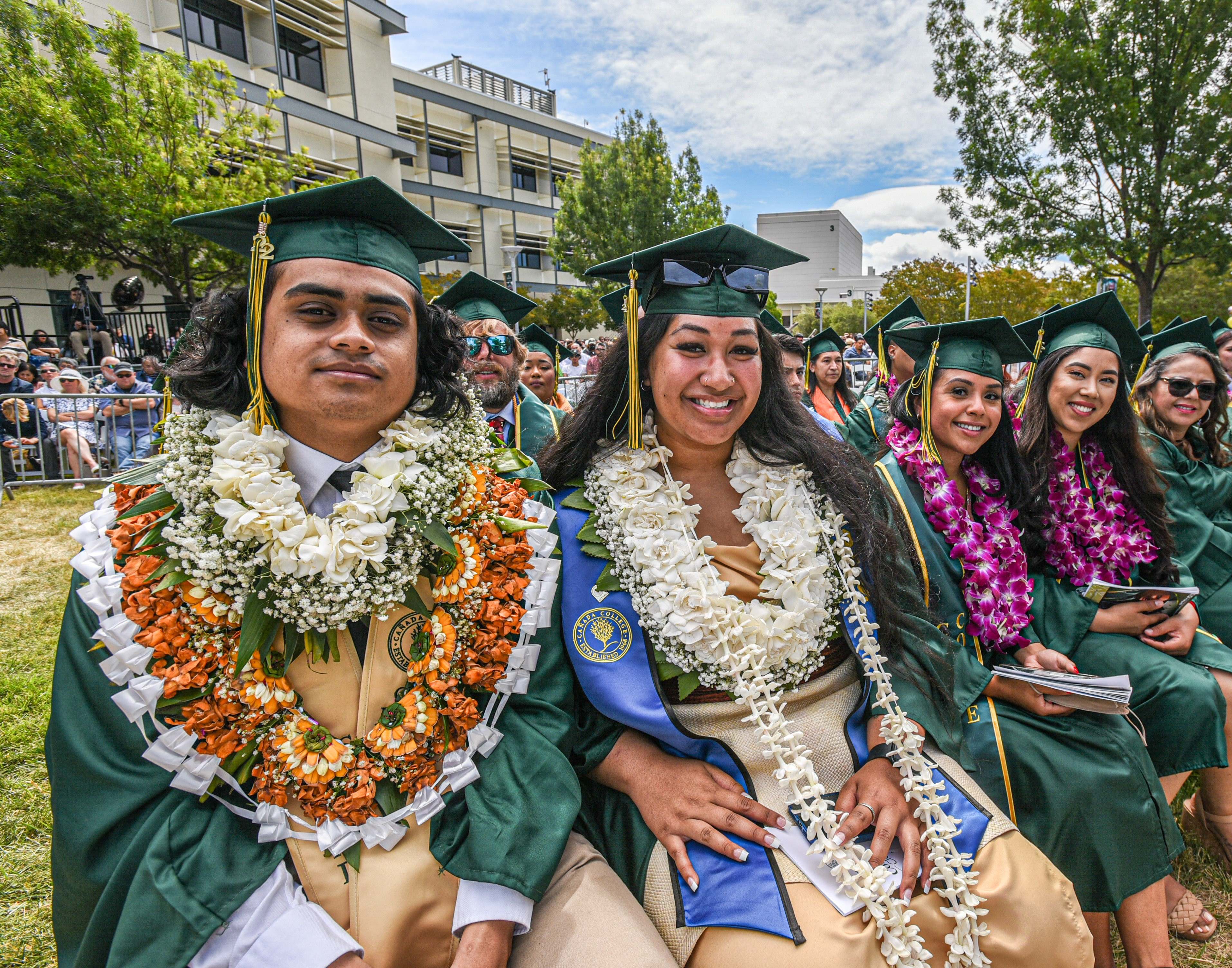 Student with lei sitting during commencement 2023