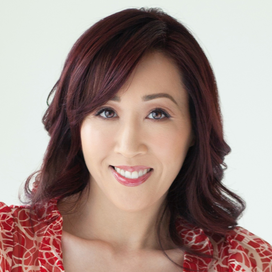 Asian American woman with curly dark hair, smiling at the camera. 