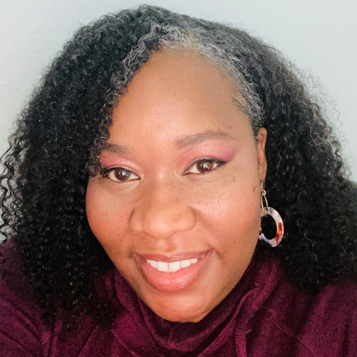 African American woman with black and grey hair, smiling at the camera. 