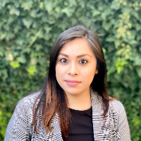 Latino woman with dark hair, wearing an elegant grey blazer.