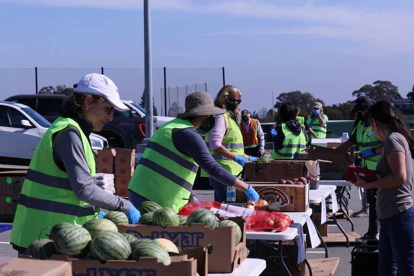 Volunteers wearing a reflective safety vest hand out food to community members on campus